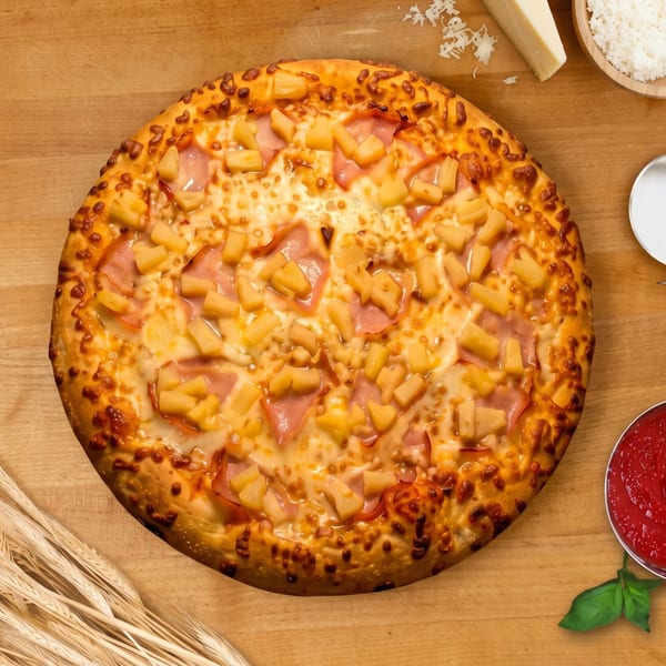 Hawaiian pizza with ham and pineapple, with wheat, cheese, sauce, and a pizza cutter.